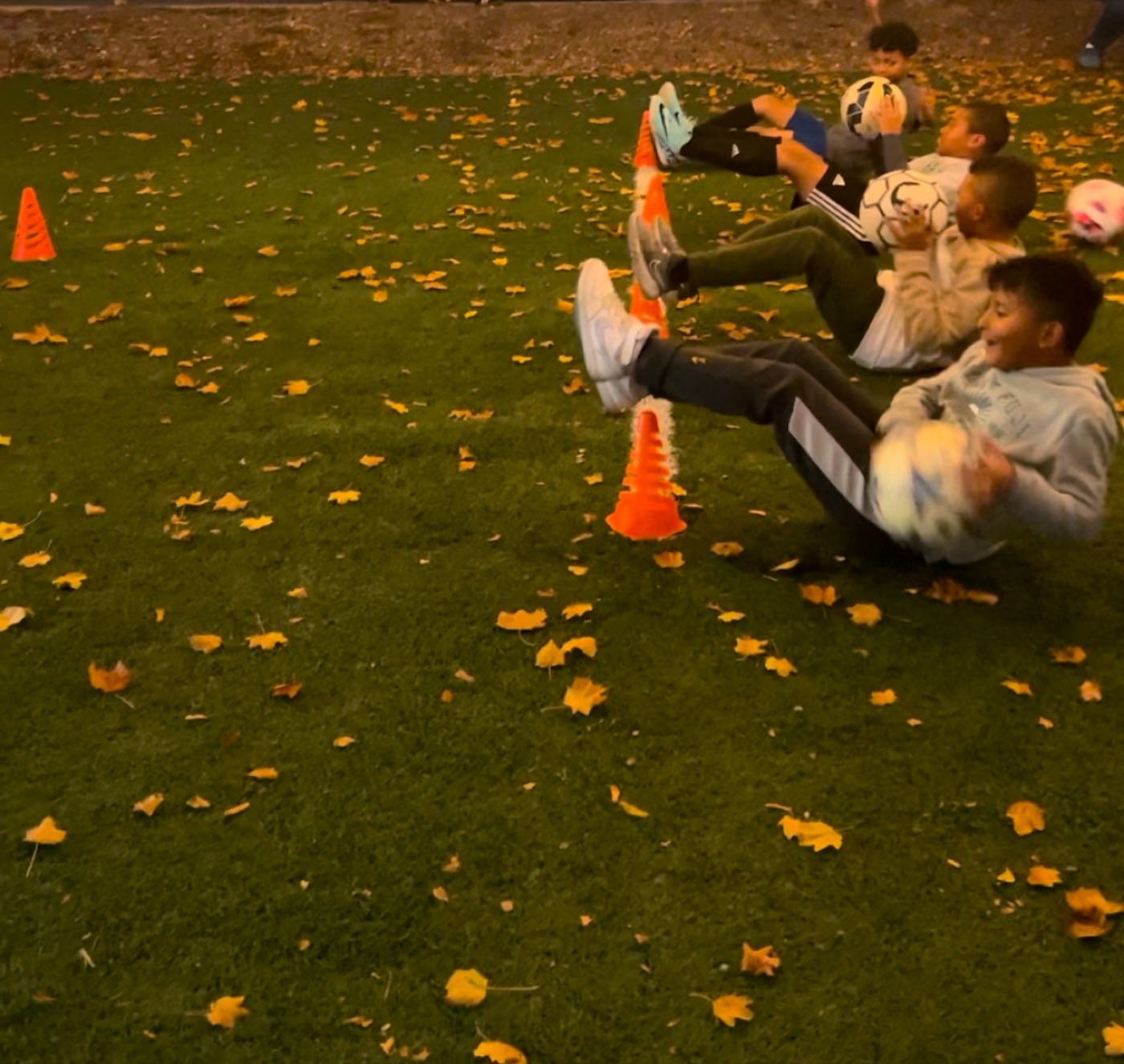 Kids doing soccer ball core drills outdoors